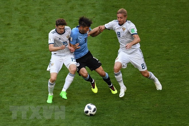  Pha tranh bóng giữa cầu thủ Rodrigo Bentancur (giữa) đội Uruguay và các cầu thủ Yuri Gazinskiy (phải) và Aleksey Miranchuk (trái) đội Nga . (Nguồn: AFP/TTXVN)