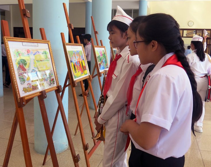 Các em học sinh xem triển lãm tranh “Thiếu nhi Quảng Bình với ATGT”.  