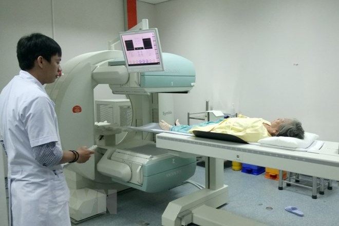 Bệnh nhân ung thư sau khi tiêm thuốc phóng xạ được đưa vào máy Spect để kiểm tra di căn ung thư xương. (Ảnh: Lê Xuân/TTXVN)