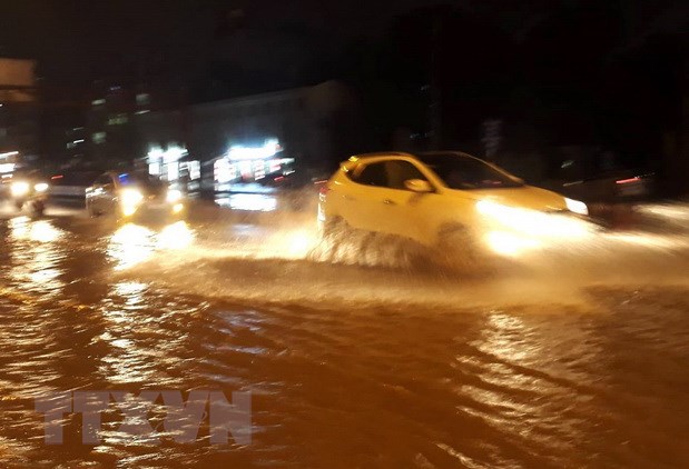 Các phương tiện di chuyển trên mặt đường Phạm Văn Đồng, quận Cầu Giấy bị ngập nước tối 15-7. (Ảnh: Văn Điệp/TTXVN)