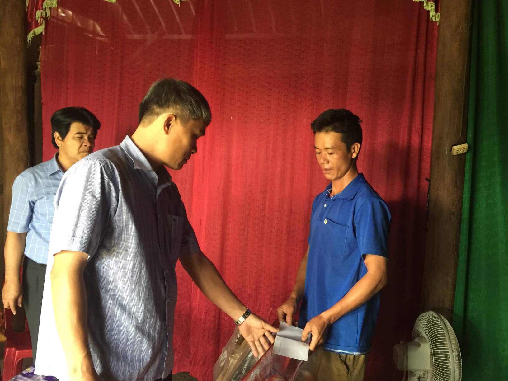 Ông Bùi Anh Tuấn, Chủ tịch UBND huyện Minh Hóa trao số tiền 20 triệu đồng cho đại diện gia đình, hỗ trợ bà Sức dựng lại nhà.