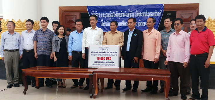 Đồng chí Phó Bí thư Thường trực Tỉnh ủy Trần Công Thuật và Đoàn đại biểu cấp cao tỉnh Quảng Bình trao số tiền hỗ trợ 10.000USD cho tỉnh Attapeu (CHDCND Lào) để khắc phục hậu quả do vỡ đập thủy điện.