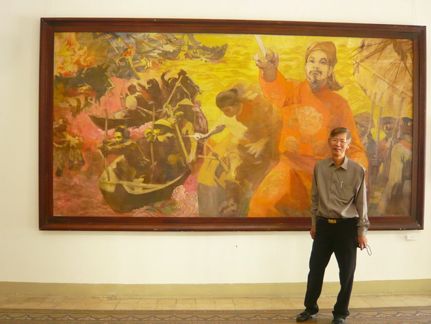 Ông Tira và một trong những bức tranh thuộc bộ sưu tập đồ sộ của mình (Ảnh Nhật Trường/Vietnam+)