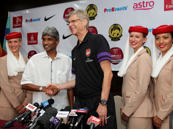   HLV Arsene Wenger (giữa) tươi cười bắt tay một lãnh đạo của hãng  hàng không Emirates. Du đấu đã trở thành một nghĩa vụ với các nhà tài trợ