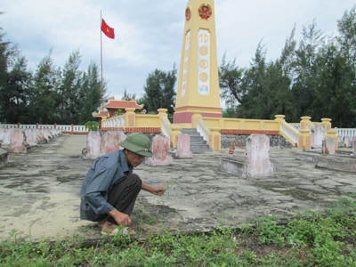 Ông Nguyễn Văn Minh đang chăm sóc khuôn viên nghĩa trang.