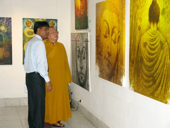 Hòa Thượng Thích Thanh Nhiễu (bên phải) giới thiệu tranh trưng bày tại triển lãm. (Ảnh: PV/Vietnam+)