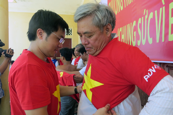 Anh Hoàng Xuân Hưng, Giám đốc Phòng giao dịch Hòa Ninh (BIDV Bắc Quảng Bình) trao áo phông cho ngư dân ở thôn Cồn Sẻ, xã Quảng Lộc (Quảng Trạch).