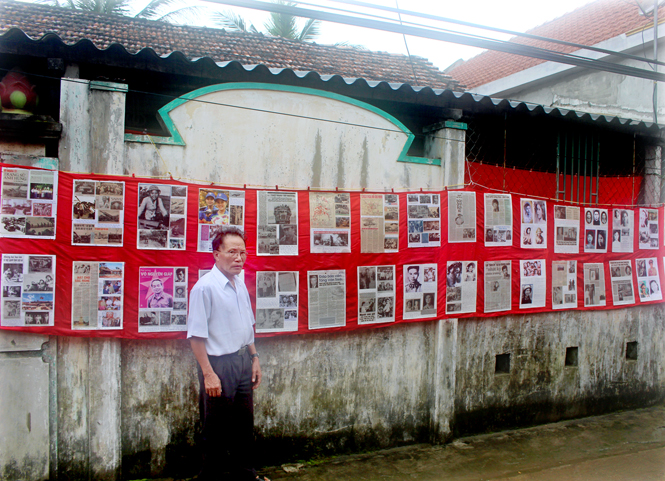 Ông Nguyễn Đình Phong bên phông tư liệu trước nhà.