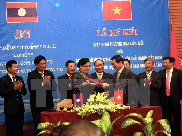 Bộ trưởng Bộ Công Thương Việt Nam Vũ Huy Hoàng và Bộ trưởng Bộ Công Thương Lào Khemmani Pholsena ký Hiệp định. (Ảnh: Tá Chuyên/TTXVN)