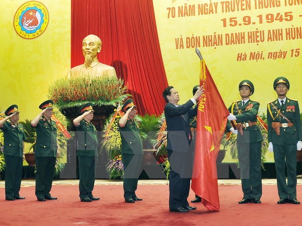 Thủ tướng Nguyễn Tấn Dũng gắn Huy hiệu Anh hùng lực lượng vũ trang nhân dân lên Cờ truyền thống của Tổng cục Công nghiệp Quốc phòng. (Ảnh: Trọng Đức/TTXVN)
