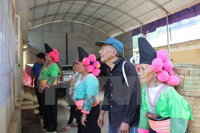 Bà con dân tộc Mông tại xã Co Mạ, huyện Thuận Châu tìm hiểu thông tin về các ứng cử viên niêm yết tại tại UBND xã. (Ảnh Công Luật/TTXVN)
