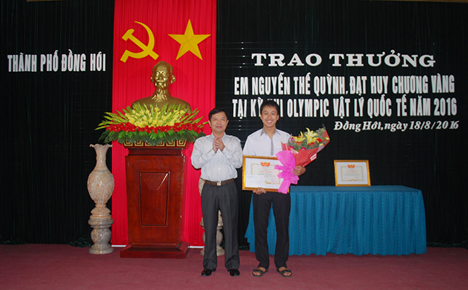 Ông Hoàng Đình Thắng, Chủ tịch UBND thành phố Đồng Hới tặng hoa chúc mừng, trao thưởng cho em Nguyễn Thế Quỳnh.