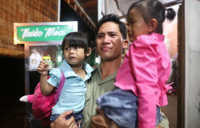  Anh Khiên chực khóc khi bế hai đứa trẻ, một con ruột (tay trái) và con nuôi (tay phải) - Ảnh chụp màn hình