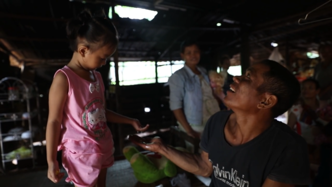 Bé Thìn hứng nước mưa trong căn nhà dột nát của bố mẹ ruột tại Bản Sóc - Ảnh chụp màn hình