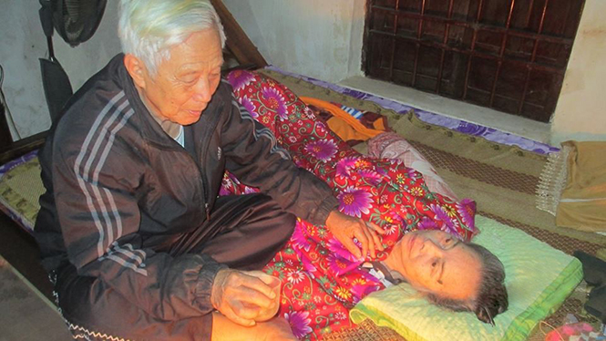  Thầy giáo Hoàng Hiếu Nghĩa đang chăm sóc vợ trên giường bệnh.