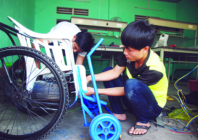 Nguyễn Mạnh Hùng và các bạn trong nhóm hoàn thành những chi tiết cuối cùng của chiếc xe lăn điện giá rẻ dành cho người khuyết tật nghèo.