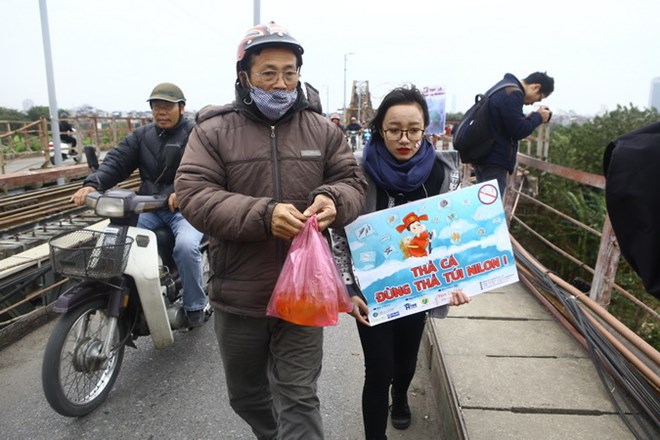 Thanh niên thủ đô với khẩu hiệu 'Thả cá không thả túi ni lông' tại khu vực cầu Long Biên để nhắc nhở người dân thủ đô trong ngày Tết ông Công, ông Táo. (Ảnh: Minh Quyết/TTXVN)
