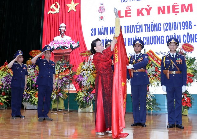 Chủ tịch Quốc hội Nguyễn Thị Kim Ngân gắn Huân chương Quân công hạng Ba lên lá cờ truyền thống của lực lượng Cảnh sát biển Việt Nam. (Ảnh: Trọng Đức/TTXVN)