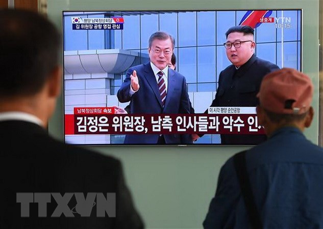 Người dân Hàn Quốc theo dõi hình ảnh truyền hình trực tiếp Nhà lãnh đạo Triều Tiên Kim Jong-un (phải, phía xa) đón Tổng thống Hàn Quốc Moon Jae-in (trái, phía xa) tại sân bay quốc tế Bình Nhưỡng ngày 18-9-2018. (Ảnh: AFP/ TTXVN)