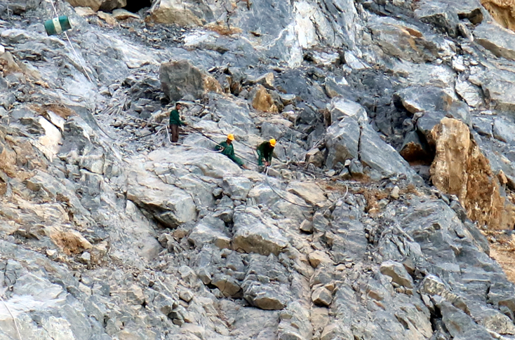 Công nhân khai thác đá đang khoan, đặt mìn để phá đá trên vách núi.