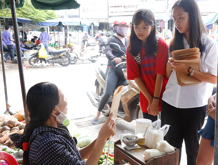 Các thành viên của dự án Less Prastic tặng lại túi giấy gấp được cho các tiểu thương chợ Đồng Hới. 