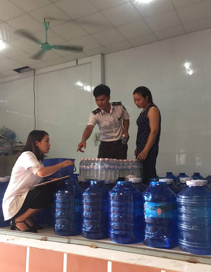 Cán bộ y tế đang thực hiện lấy mẫu để kiểm nghiệm chất lượng nước đóng chai. 
