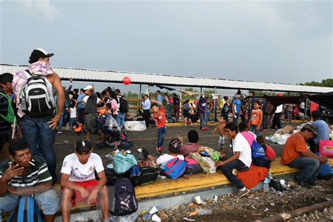 Người di cư từ Honduras chờ để vượt qua biên giới giữa Ciudad Tecun Uman (Guatemala) và Ciudad Hidalgo (Mexico) trong hành trình tới Mỹ ngày 21/10/2018. (Ảnh: AFP/ TTXVN)