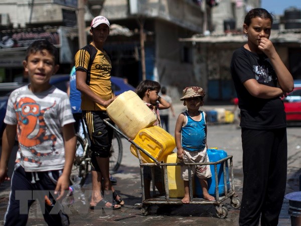 Người dân Palestine xếp hàng lấy nước sinh hoạt tại một trại tị nạn ở Dải Gaza. (Ảnh: AFP/TTXVN)