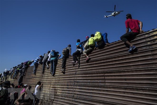 Người di cư vượt qua hàng rào biên giới giữa Mỹ và Mexico, gần cửa khẩu El Chaparral ở Tijuana, bang Baja California, Mexico ngày 25-11-2018. (Ảnh: AFP/TTXVN)