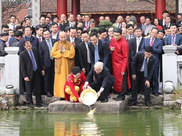 Tổng Bí thư, Chủ tịch nước Nguyễn Phú Trọng và Phu nhân thả cá chép tại hồ Hoàn Kiếm. (Ảnh: Trí Dũng/TTXVN)