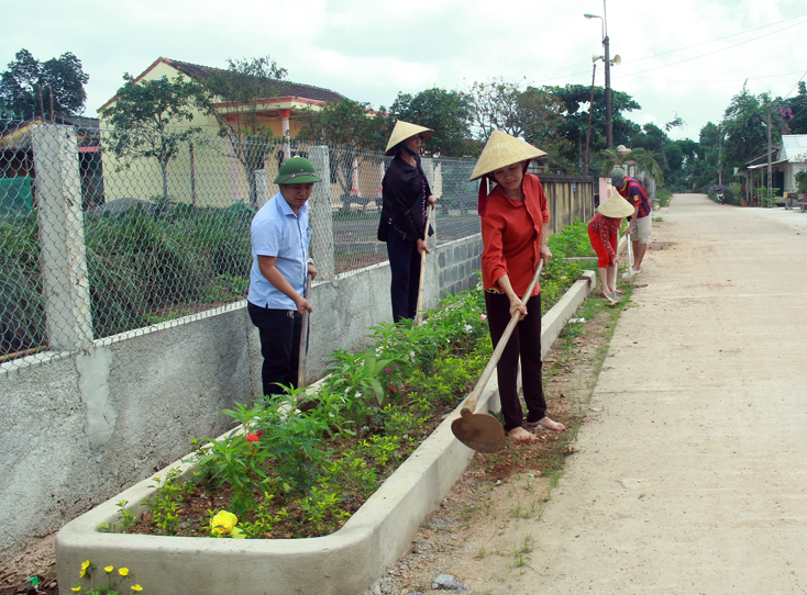 Anh Đinh Minh Quân (người đội mũ cối) đang cùng bà con Xuân Lai chăm sóc tuyến đường hoa ở thôn.