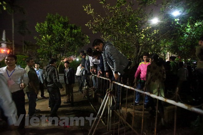  Nhiều người dân thừa lúc lực lượng an ninh không để ý đã nhanh chóng trèo rào nhảy vào bên trong để xin ấn tại lễ khai ấn đền Trần (Nam Định) năm 2019. (Ảnh: Vietnam+)