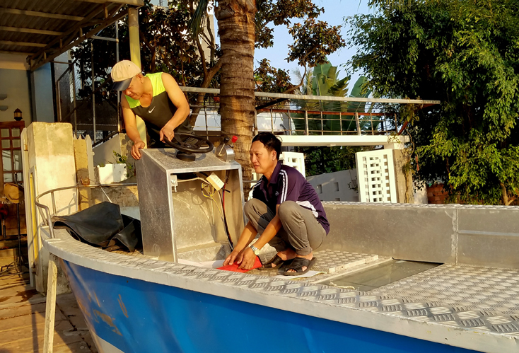 Anh Hùng đang sửa lại chiếc thuyền nhôm nhỏ để phục vụ du khách đi câu mực ven bờ biển Nhật Lệ.