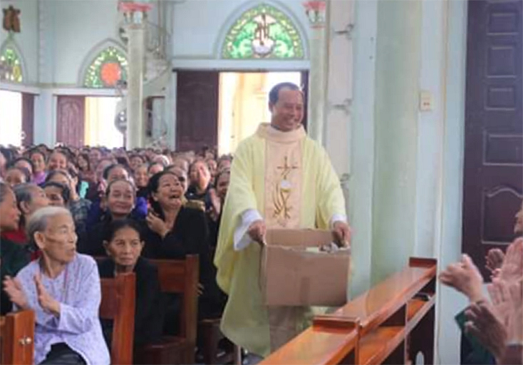 Linh mục Nguyễn Xuân Đình mặc áo lễ bưng thùng tiền  
