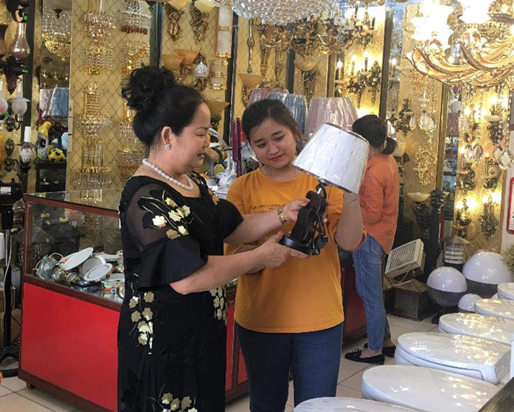 Chị Đoàn Thị Dương (bên trái) đang giới thiệu cho khách các loại đèn trang trí trong cửa hàng.