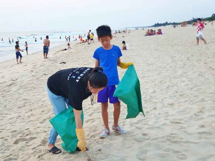 Mẹ và con cùng nhau nhặt rác làm sạch bãi biển