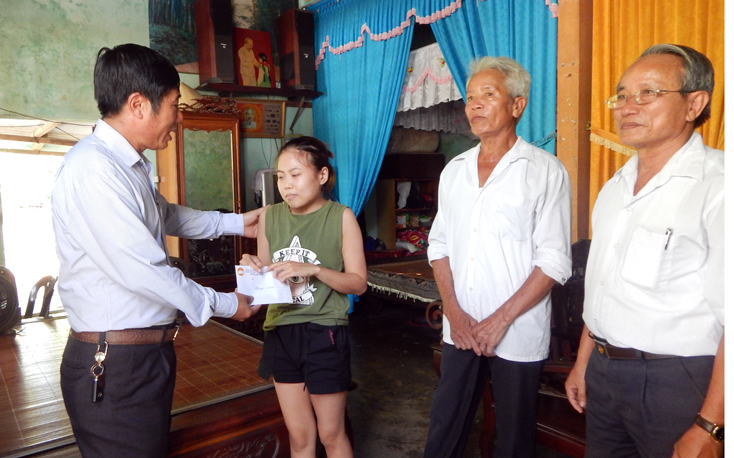Đồng chí Lê Duy Hưng, Chủ tịch Ủy ban Mặt trận TQVN huyện Bố Trạch tặng quà cho cháu Nguyễn Thị Phương Thảo