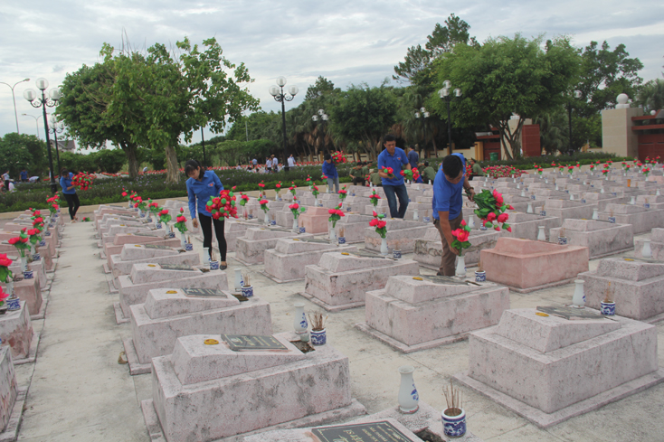 Các đoàn viên thanh niên thay bình hoa tại phần mộ các anh hùng, liệt sỹ.  