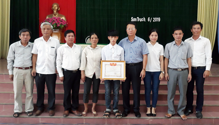 Lãnh đạo huyện Bố Trạch trao giấy khen biểu dương hành động dũng cảm cứu người bị đuối nước của em Trần Văn Nam.