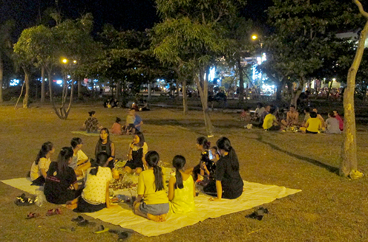 Nhiều nhóm ngồi ăn uống trên bãi cỏ trong công viên Nhật Lệ. Ảnh chụp tối 30-6-2019.