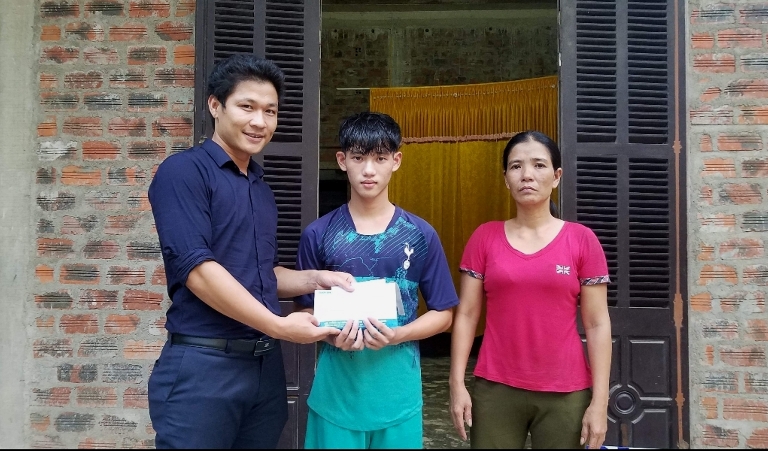 Đại diện Báo Tuổi Trẻ trao số tiền bạn đọc hỗ trợ cho em Trần Văn Nam.