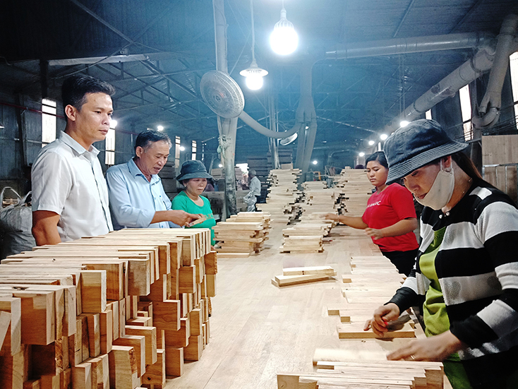 Ông Trần Ngọc Sỹ (ở giữa, bên trái) tại nhà máy chế biến gỗ của mình.