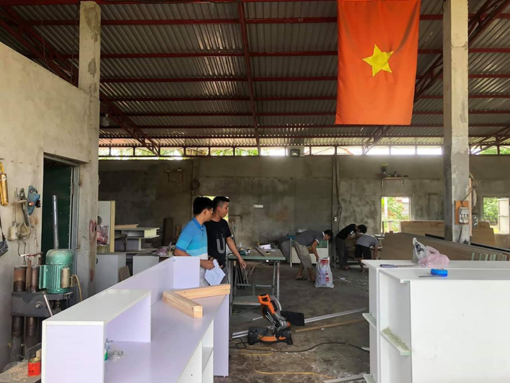 Anh Nguyễn Quang Huy (áo đen) đang làm việc tại cơ sở sản xuất mặt hàng nội thất gia đình bằng chất liệu gỗ công nghiệp. 