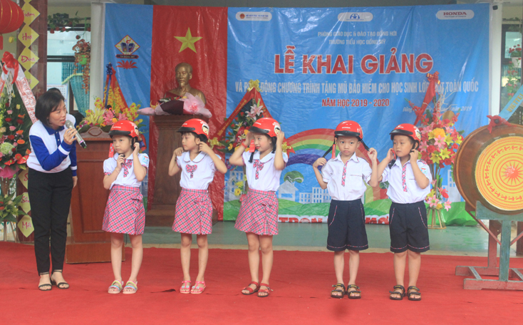Đại diện Công ty Honda Việt Nam hướng dẫn các em học sinh lớp 1 đội mũ bảo hiểm đúng cách để bảo đảm an toàn khi tham gia giao thông.