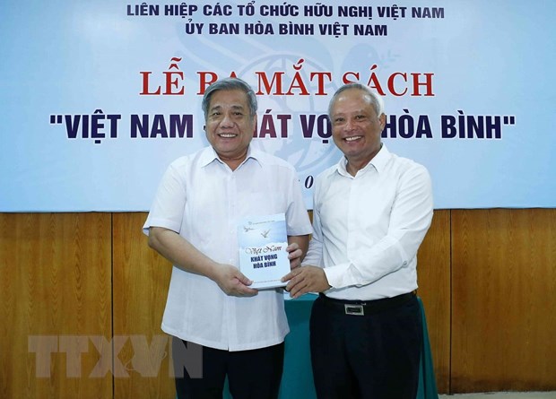 Ông Uông Chu Lưu, Ủy viên Trung ương Đảng, Phó Chủ tịch Quốc hội, Chủ tịch Ủy ban Hòa bình Việt Nam tặng sách cho các đại biểu. (Ảnh: Văn Điệp/TTXVN)