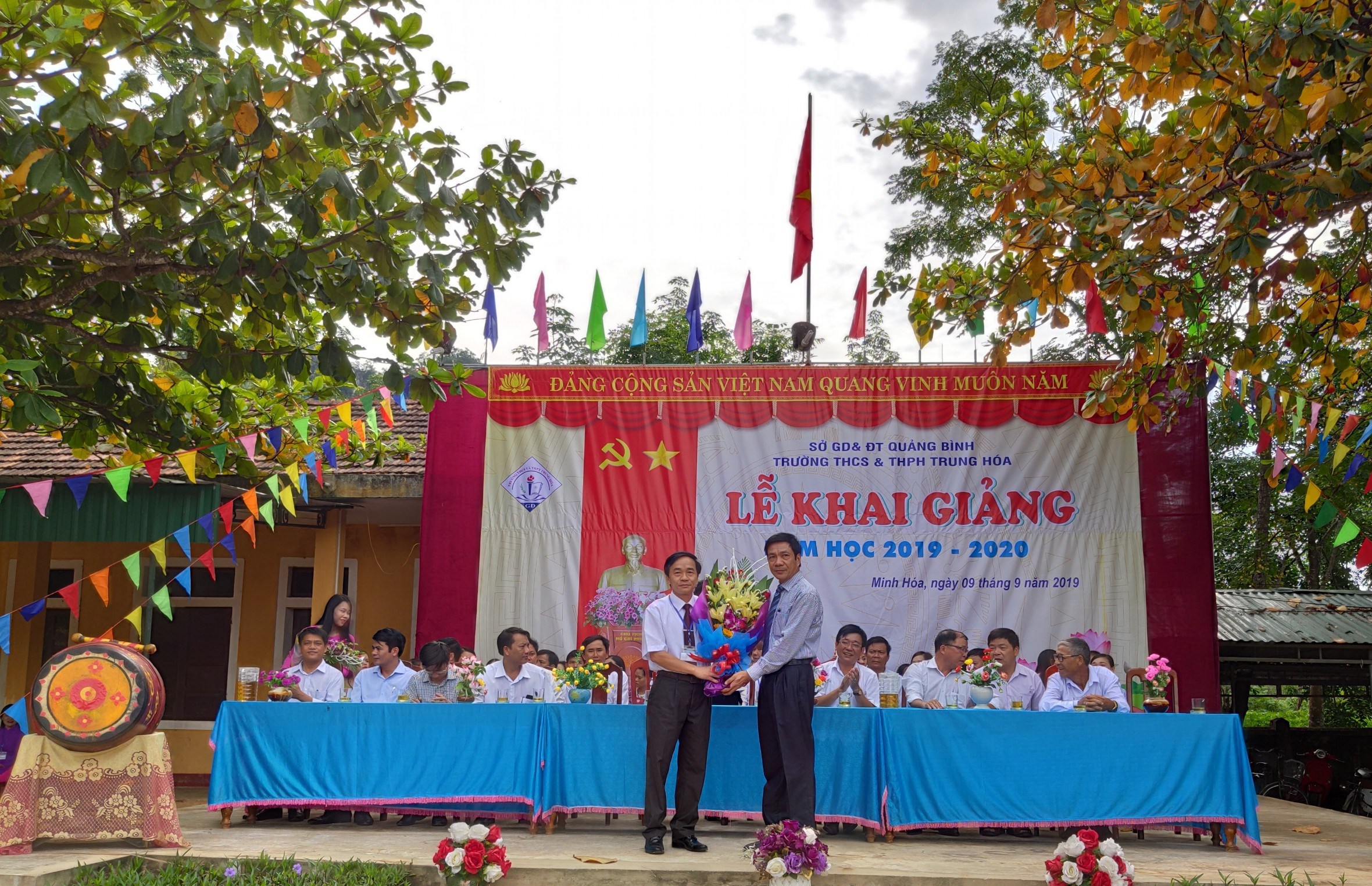 Đồng chí Trưởng ban Dân vận Tỉnh ủy Nguyễn Công Huấn tặng hoa chúc mừng thầy và trò Trường THCS và THPT Trung Hóa nhân lễ khai giảng năm học mới.