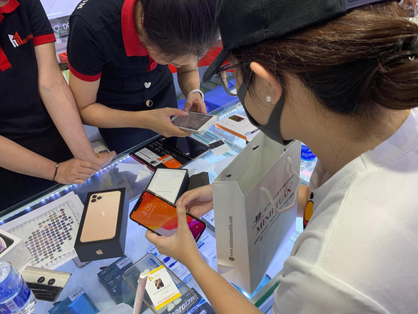 Một khách hàng nữ tìm hiểu mua iPhone 11 tại một cửa hàng ở Q.1, TP.HCM - Ảnh: PHAN QUỐC