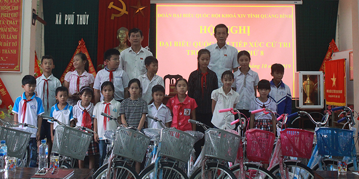 Các ĐBQH trao xe đạp cho các em học sinh ở xã Phú Thủy. 