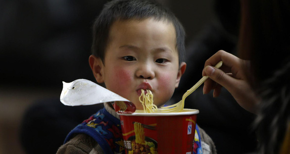 Một em bé người Trung Quốc được mẹ đút ăn mì gói - Ảnh: REUTERS