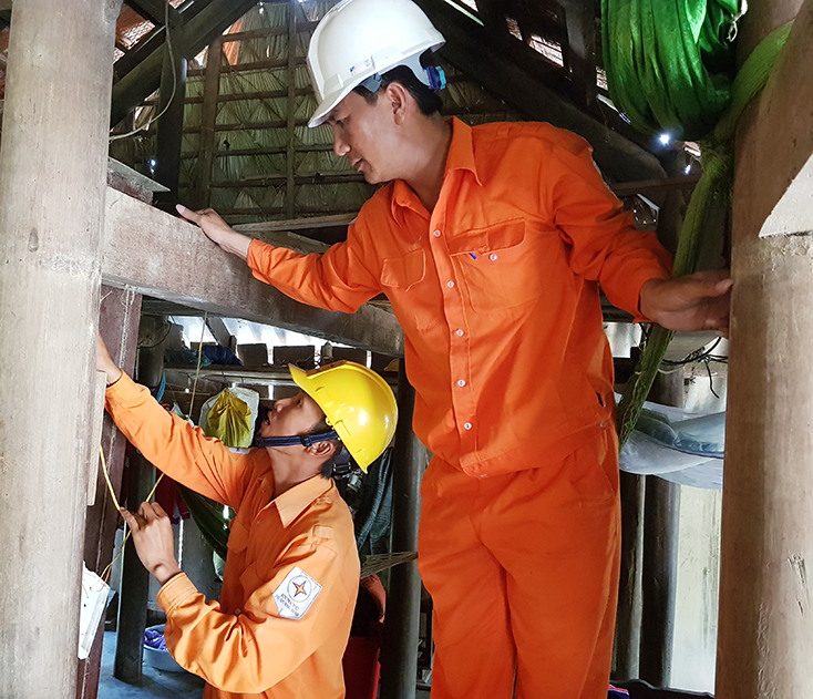 Công nhân PC Quảng Bình sửa chữa, thay thế bảng điện, bóng đèn sau công tơ cho hộ gia đình có hoàn cảnh khó khăn tại xã Ngư Hóa (Tuyên Hóa).